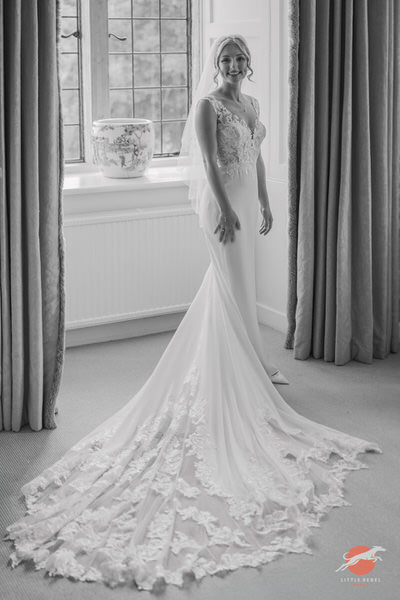 Black-and-white portrait of a bride showing the lace train of her wedding dress at Askham Hall