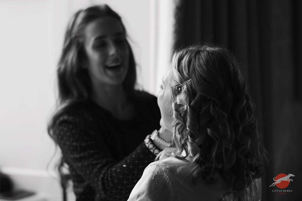 Black-and-white photograph of a bride having her make-up applied at Askham Hall