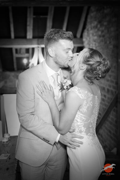 Black-and-white photograph of newlyweds kissing during their reception at Askham Hall