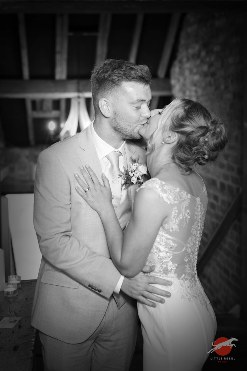 Black-and-white photograph of newlyweds kissing during their reception at Askham Hall