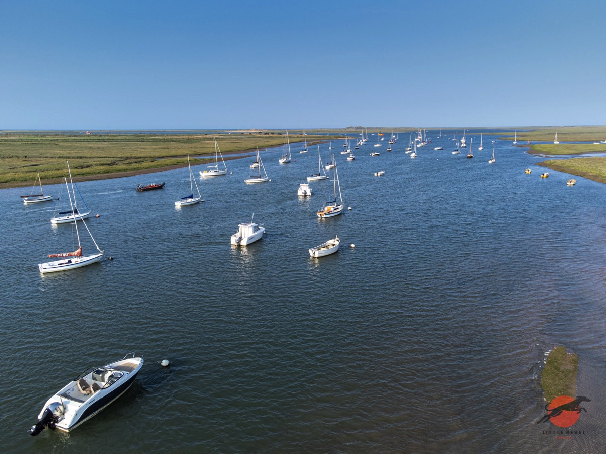 Aerial view of sailing boats moored in a tidal channel on the North Norfolk coast