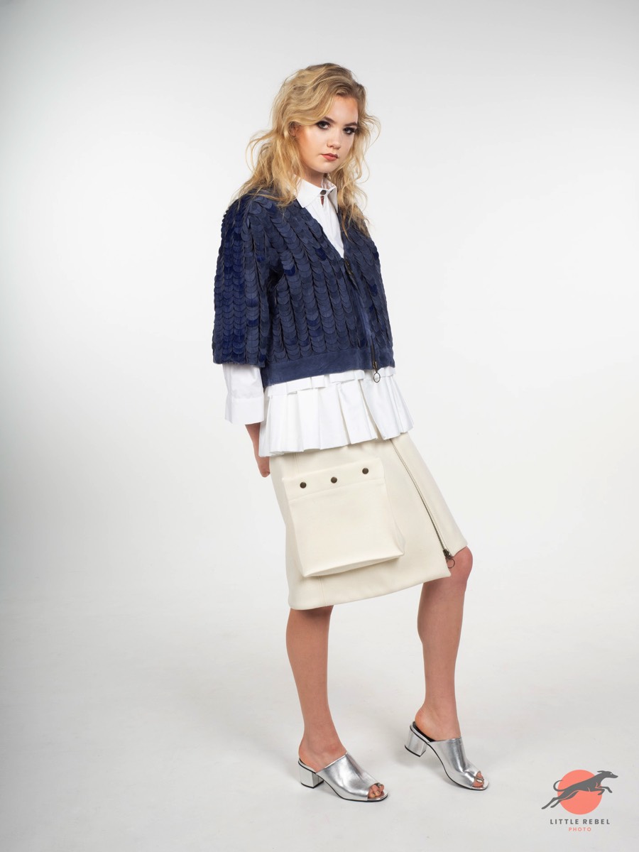 Model wearing a textured blue jacket, pleated white shirt and cream skirt during a University of Huddersfield fashion shoot