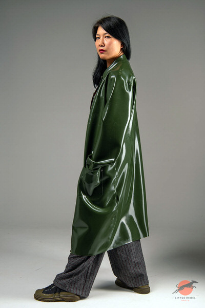Female model wearing a glossy olive-green rubber raincoat by Wrapped in Rubber